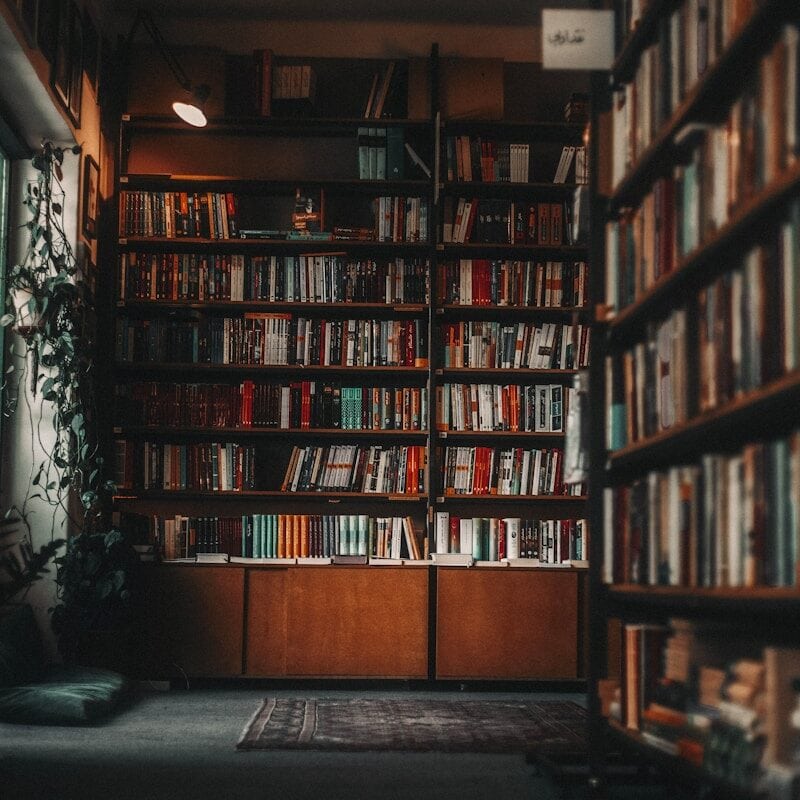 a bookshelf filled with lots of books next to a window